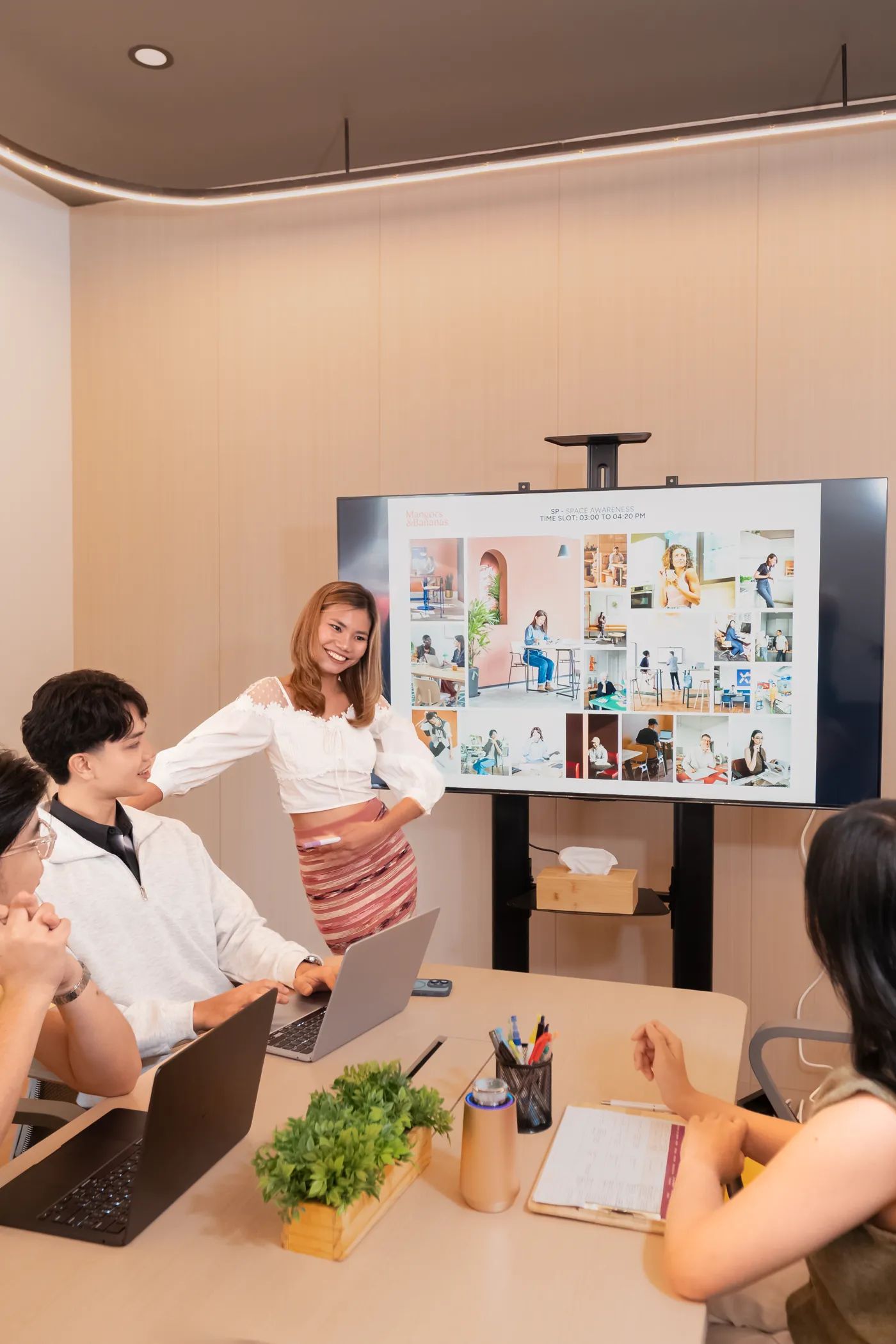 Team meeting inside the Mangoes and Bananas conference room with a presentation screen.