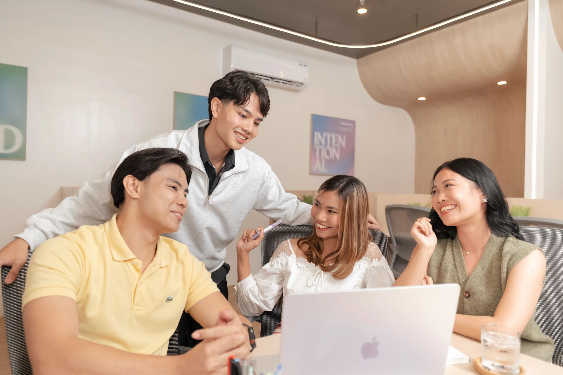 A group of people collaborating around a laptop inside Mangoes and Bananas coworking space in Malolos, Bulacan.