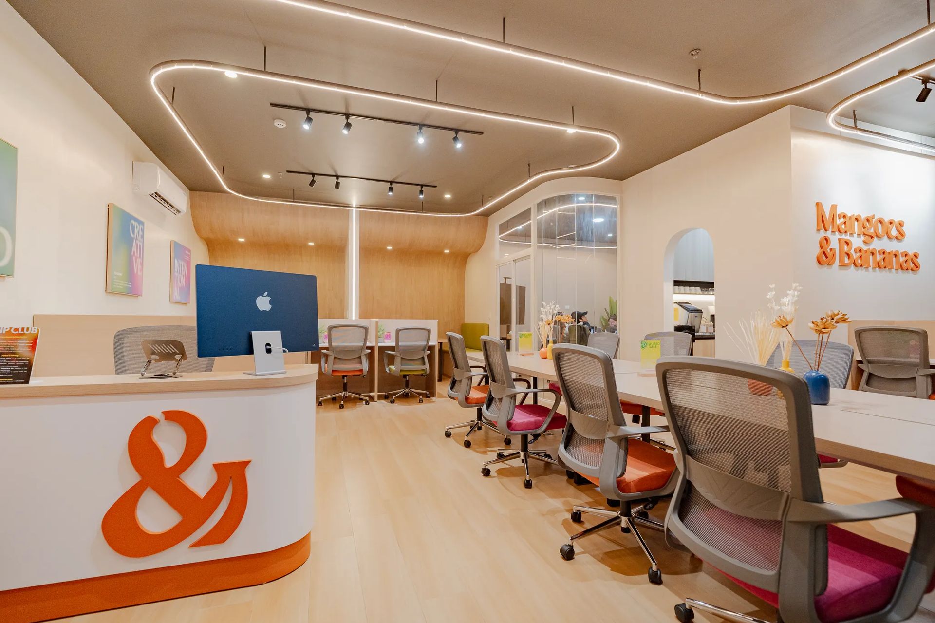 Wide view of Mangoes and Bananas coworking space with desks, chairs, and reception area.