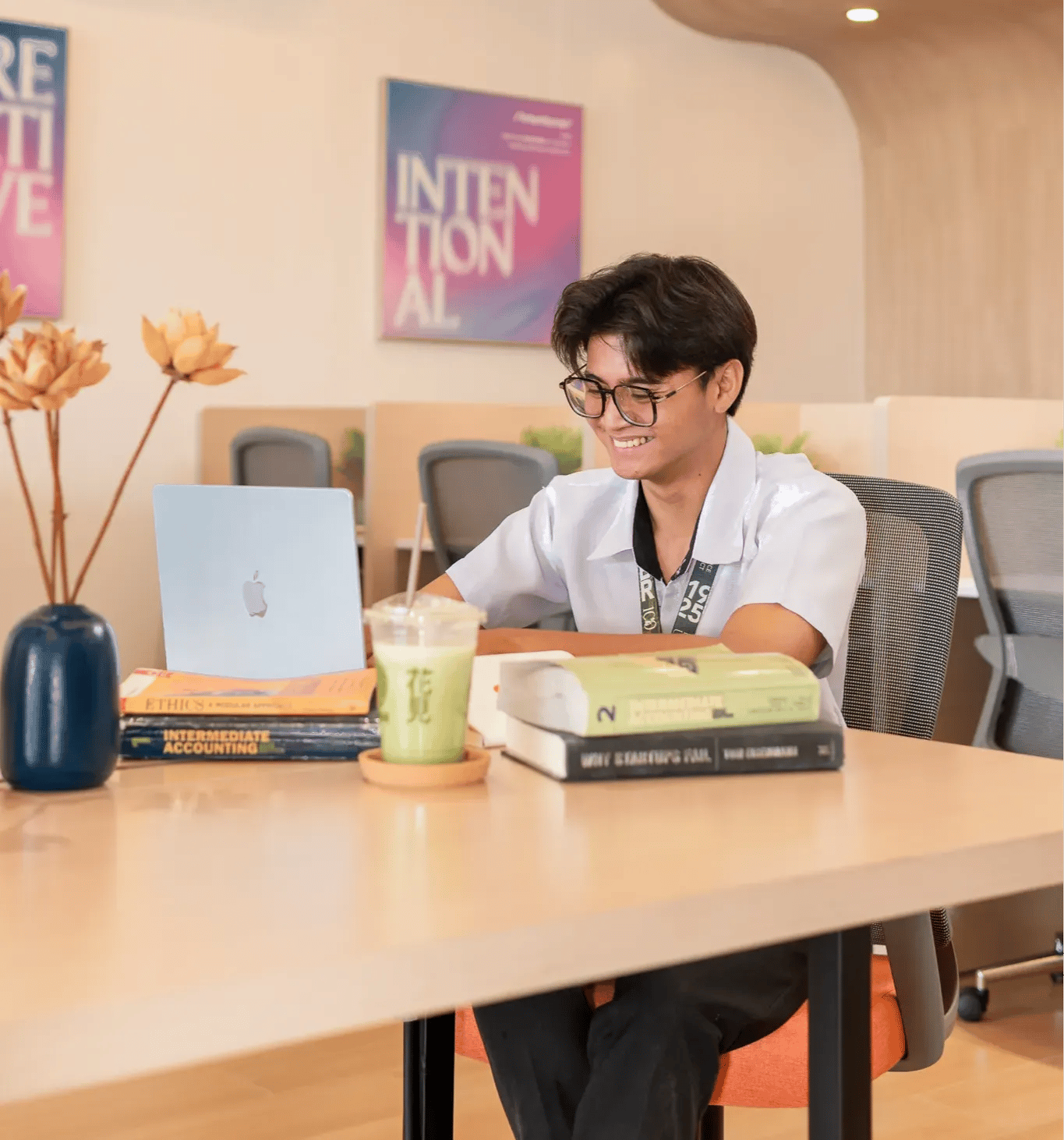 Student working on a laptop with books inside Mangoes and Bananas coworking space.