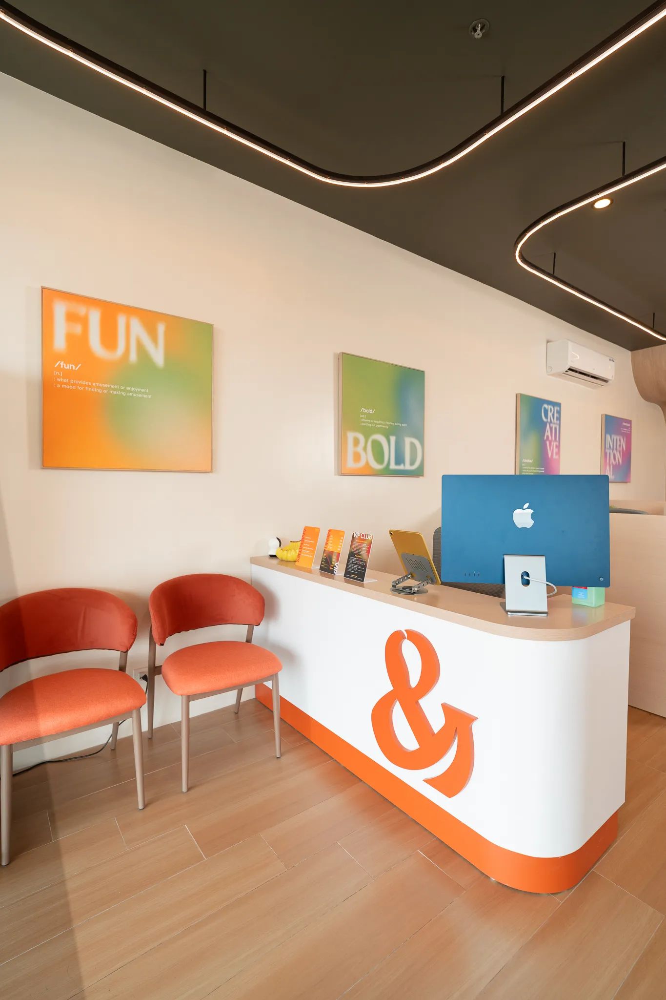 Reception area of Mangoes and Bananas coworking space with branded front desk and waiting chairs.