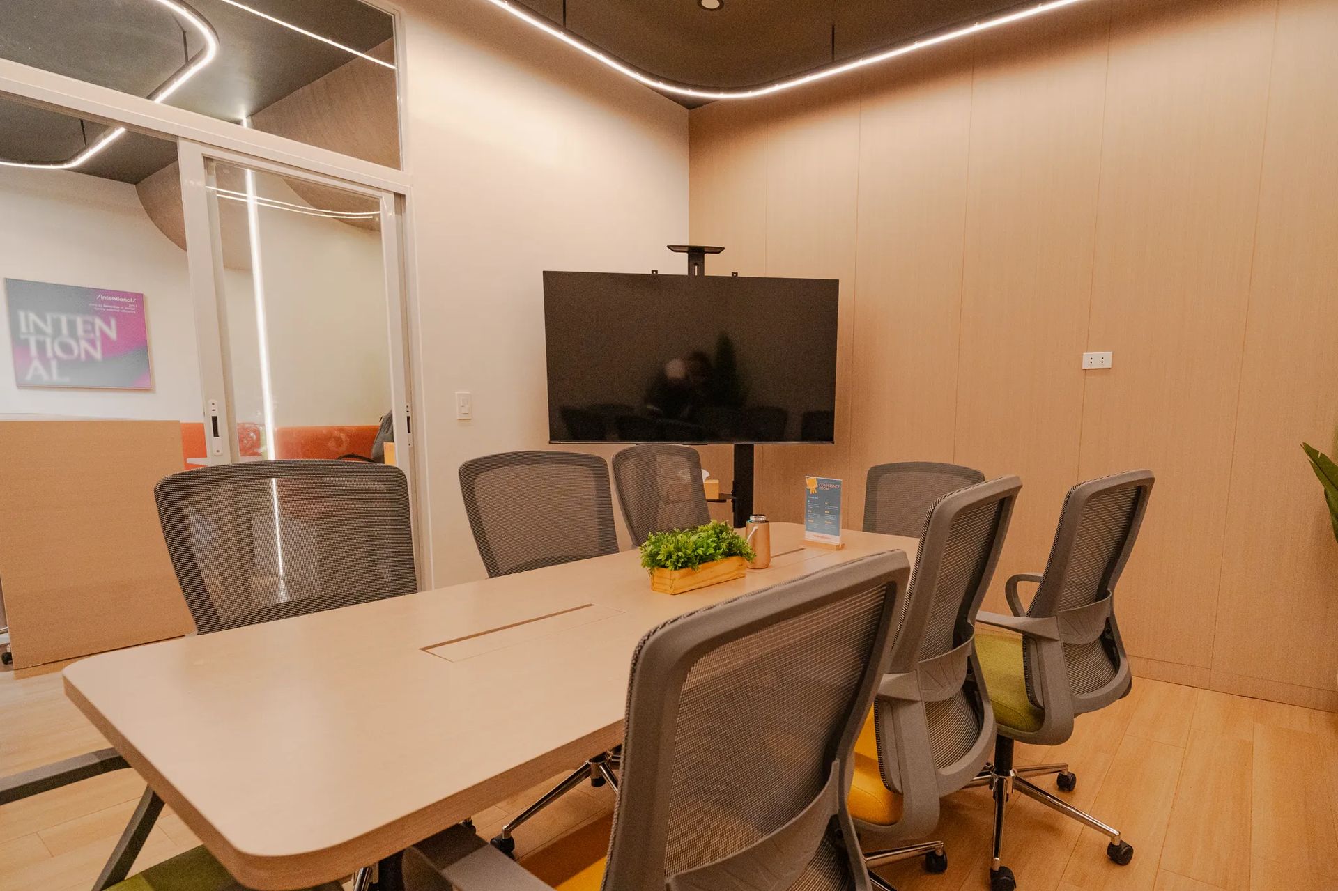 Conference room setup with table, chairs, and display screen inside Mangoes and Bananas coworking space.