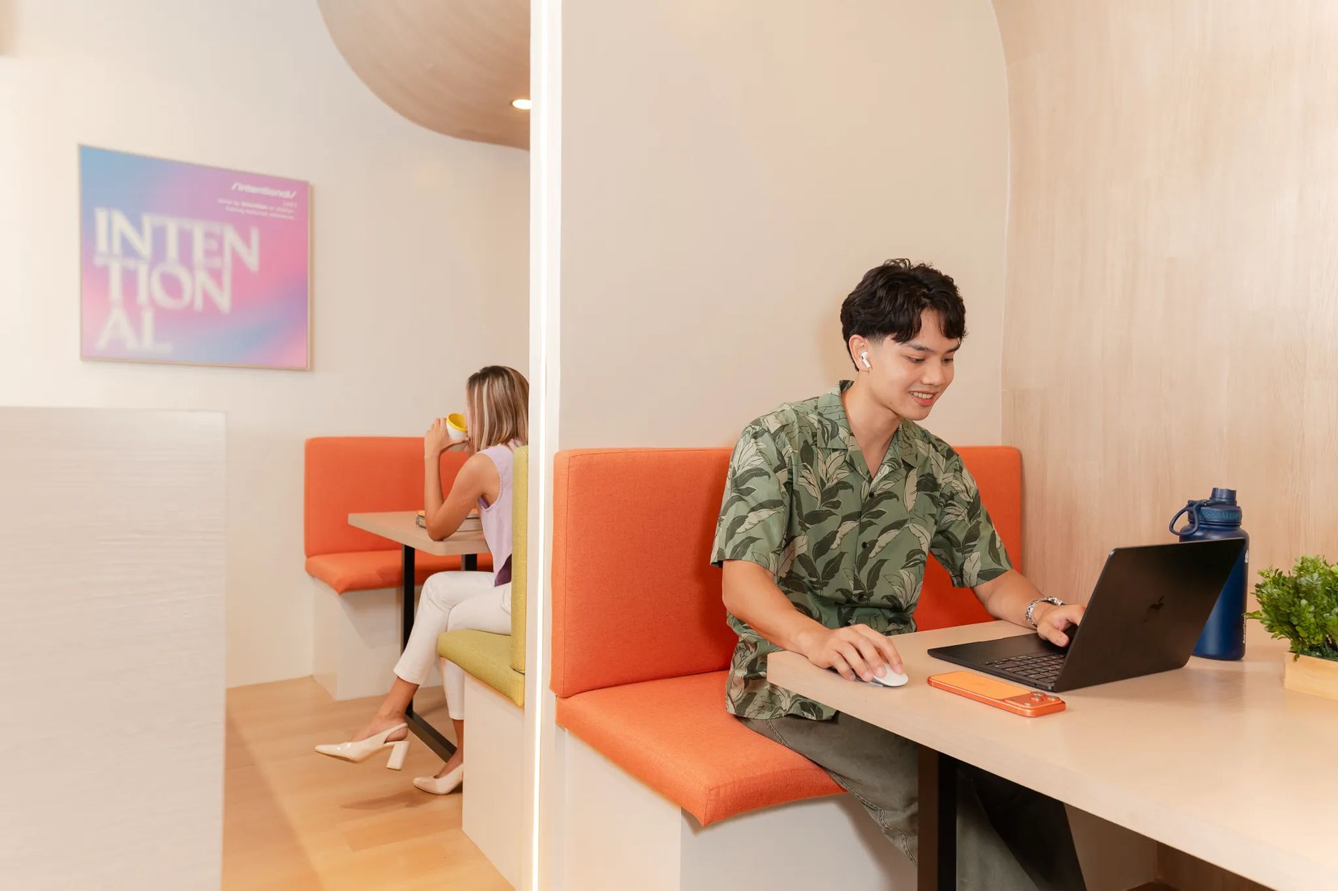 Person working on a laptop in a booth seat inside Mangoes and Bananas coworking space.