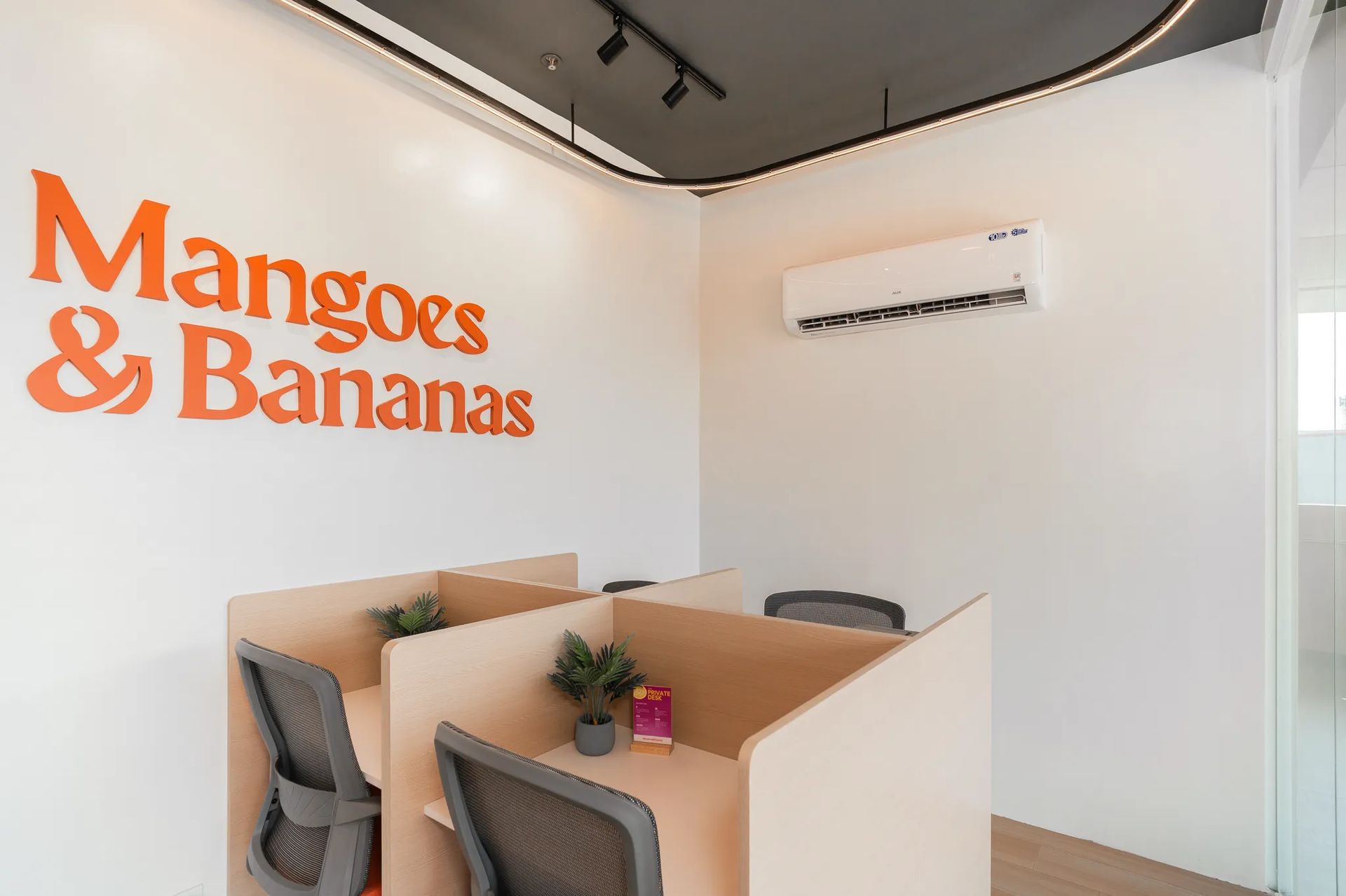 Private desk area inside Mangoes and Bananas coworking space with branded wall signage.